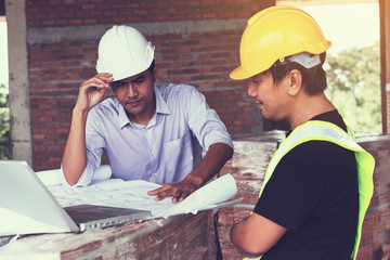 engineer working on checking progress of construction with blueprint at construction site