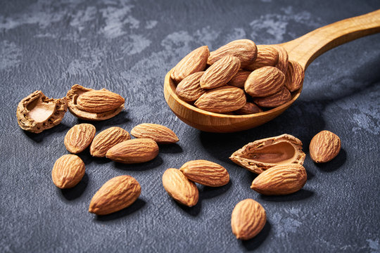 Almonds   in wooden spoon  on black table,close-up