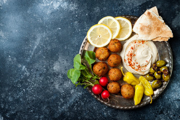 Fototapeta na wymiar Middle Eastern meze platter with falafel, pita, hummus, pickles, radishes. Mediterranean or greek appetizer party idea