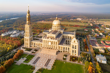 Fototapeta na wymiar Sanctuary and Basilica of Our Lady of Licheń in small village Lichen. The biggest church in Poland, one of the largest in the World. Famous Catholic pilgrimage site. Aerial view in fall. Sunset light