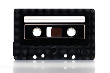 Old vintage black cassette with blank white label on white background. Copy space.
