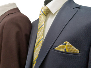 Two formal dark grey and brown business suits on an exhibition isolated on white background, close up.