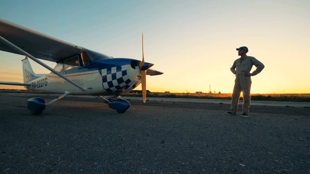 Male aviator looks at his light airplane, side view.