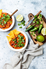 Vegetarian chili con carne with lentils, beans, nachos, lime, jalapeno. Mexican traditional dish