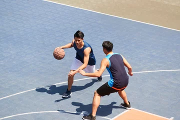 Tuinposter high angle view of young asian adults playing basketball outdoors © imtmphoto