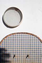 pared blanca soleada con un cedazo colgado encima de una fuente de 2 grifos dorados y azulejos de cerámica artesana