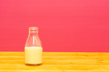 Glass milk bottle half full with banana milkshake