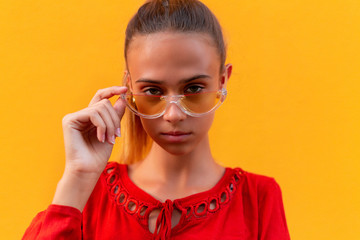 Beautiful positive fashionable stylish modern brunette girl in trendy glasses looking at camera. Cute lovely teenager person with tender kind simple face. Soft focus portrait.