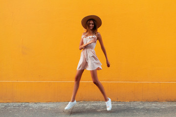 Portrait of playful crazy girl jumping in the air looking at camera enjoying weekend having perfect mood isolated on yellow background