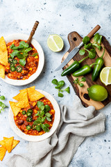 Vegetarian chili con carne with lentils, beans, nachos, lime, jalapeno. Mexican traditional dish