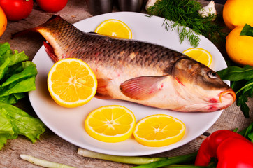 Fresh  Cyprinus carpio carpio   fish on wooden cutting board with tomatoes