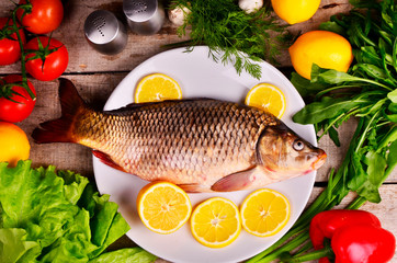 Fresh  Cyprinus carpio carpio   fish on wooden cutting board with tomatoes