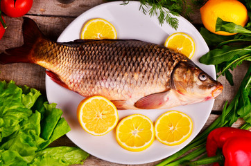 Fresh  Cyprinus carpio carpio   fish on wooden cutting board with tomatoes
