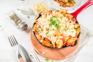 Baked creamy pasta casserole, mac and cheese with minced meat, italian ground beef bolognese casserole, dark blue concrete background copy space
