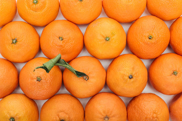 top view of whole ripe tangerines with green leaves on white background