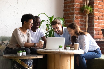 Diverse friends sitting in cafe watching funny videos using computer