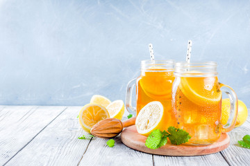 Iced summer drink, tea with lemon slices and mint, rustic wooden background copy space
