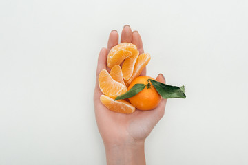 cropped view of woman holding peeled tangerine slices and whole tangerine on white background