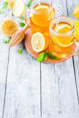 Iced summer drink, tea with lemon slices and mint, rustic wooden background copy space