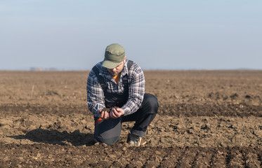 Young farmer dirt while tractor is plowing field