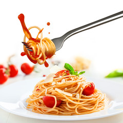 Person takes a fork with spaghetti from the plate with pasta and parmesan.