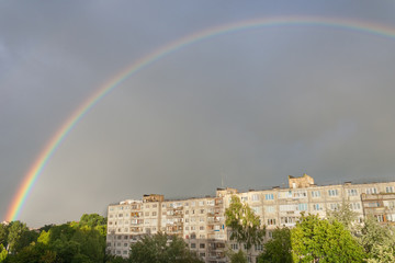 General view of a large bright double rainbow over the city. A double rainbow appeared after the rain in the sky over single-family houses. Joy for the townspeople after the storm.