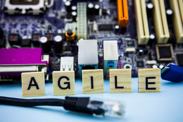Fototapeta na wymiar Word AGILE on the wooden blocks with computer technology mainboard background. IT concept image background