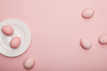 Top view of painted easter eggs on plate on pink background