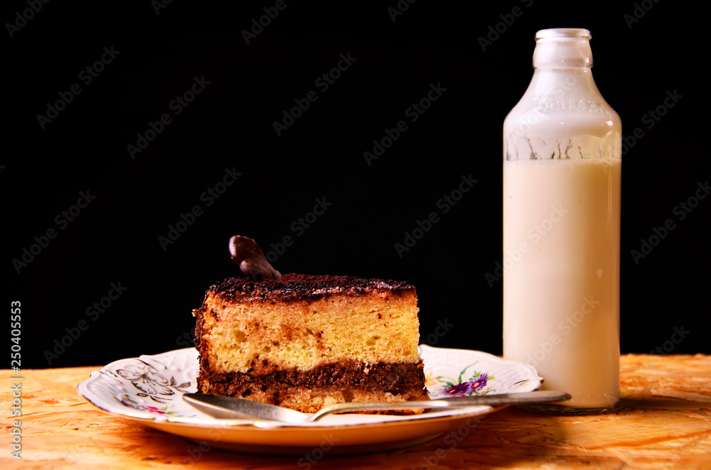 Wall mural piece of cake with the bottle of milk on the tablecloth