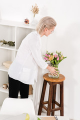  woman looking at flowers in vase in modern office