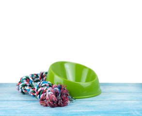 Pet toy and plastic bowl with copy space on wooden table.  Pet accessories concept