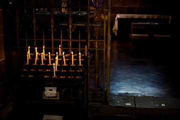 Candle flames in the Christian church. Group of yellow candles at the church. Dark mood with burnt candles