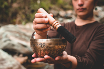 woman holding and playing a singing bowl tibetan bowl