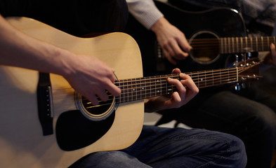 Fototapeta na wymiar Two people duet playing a melody on acoustic six-string guitars at home in ordinary everyday clothes