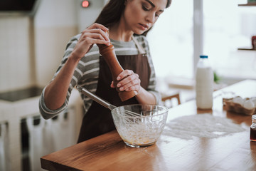 Woman is adding spices to dish in kitchen