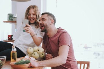 Cute little girl using cellphone and spending time with her dad