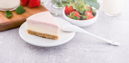 Delicious and nutritious handmade strawberry no bake frozen gradient colour fromage frais cheesecake slice with raw sarcocarp besides isolated with fair-faced gray background, copy space, close up