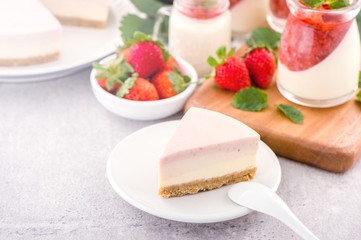 Delicious and nutritious handmade strawberry no bake frozen gradient colour fromage frais cheesecake slice with raw sarcocarp besides isolated with fair-faced gray background, copy space, close up