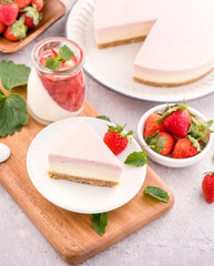 Delicious and nutritious handmade strawberry no bake frozen gradient colour fromage frais cheesecake slice with raw sarcocarp besides isolated with fair-faced gray background, copy space, close up