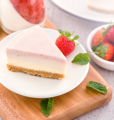 Delicious and nutritious handmade strawberry no bake frozen gradient colour fromage frais cheesecake slice with raw sarcocarp besides isolated with fair-faced gray background, copy space, close up