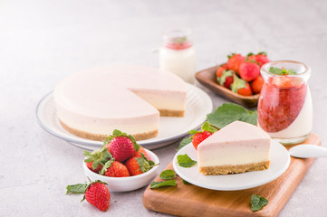 Delicious and nutritious handmade strawberry no bake frozen gradient colour fromage frais cheesecake slice with raw sarcocarp besides isolated with fair-faced gray background, copy space, close up