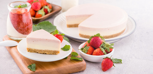 Delicious and nutritious handmade strawberry no bake frozen gradient colour fromage frais cheesecake slice with raw sarcocarp besides isolated with fair-faced gray background, copy space, close up