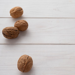 Walnuts on white wooden background.
