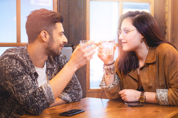 Young couple toasting with alchool glasses on a pub