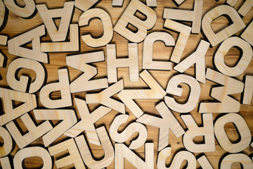 Random wooden block letters lying on wooden surface. Top view.