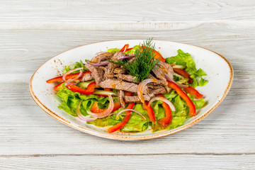 Salad with meat, pepper, herbs and onions shot on a white background