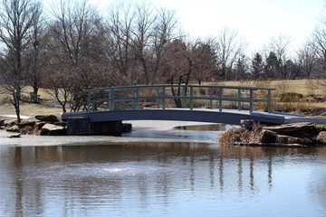 The wooden footbridge over the pond in the park. - Powered by Adobe