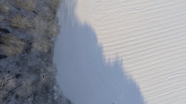 Downwards facing shot of snow covered forrest and fields at sunny winter day shortly after sunrise