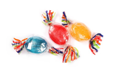 Colorful hard candies in transparent cellophane wrapping, isolated on white background, top view