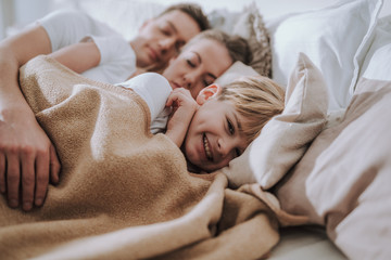 Happy child smiling while his parents sleeping